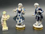 three figurines of people standing next to each other on a table