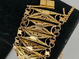a close up of a gold bracelet on a black display stand