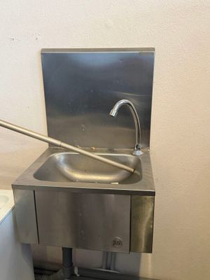 un lavabo en acier inoxydable dans une salle de bains, équipé d'un robinet en métal