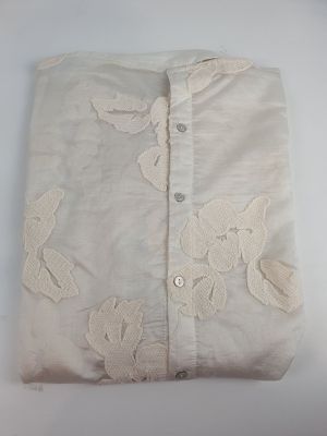 embroidered shirt with white flowers on it on a white surface