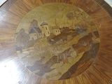a wooden table with a painting on it in the middle of a room