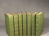 six livres verts sont empilés les uns sur les autres sur une surface grise