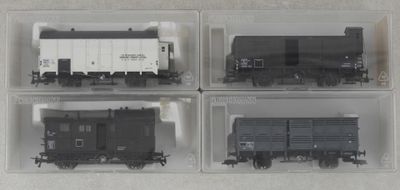 quatre boîtes en plastique contenant quatre types de trains différents, posées sur une surface blanche