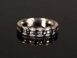 a close up of a diamond and sapphire ring on a black surface