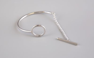silver bracelet with a bar and a chain on a white surface