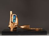 bronze sculpture of a pipe with a blue stone in the mouth