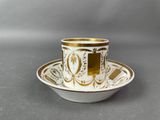an image of a cup and saucer with a gold and white design