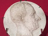 une image représentant le visage d'un homme sur une plaque posée sur un fond rouge