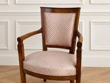 La chaise est en bois et dispose d'une assise rembourrée de couleur rose.