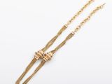 un collier en or composé d'une longue chaîne et d'un nœud