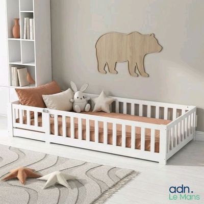 une photo d'une chambre de bébé avec un berceau blanc et un ours en peluche accroché au mur