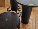 a black table and two stools on a tiled floor