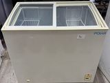 a white chest freezer sitting on top of a floor next to a wall