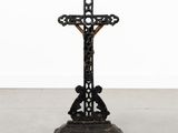 a black cross on a wooden stand with a white background