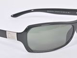 lunettes de soleil posées sur une surface blanche, avec une monture noire et des verres verts