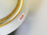 un vase blanc bordé d'or et portant une étiquette