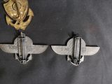 three silver metal badges and a gold medal hang on a black cloth