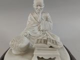 a statue of a man sitting on a table with a book