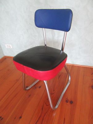 une chaise rouge avec une assise bleue posée sur un plancher en bois