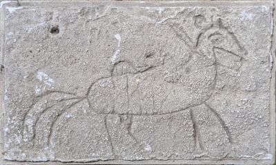 a stone plaque with a drawing of a man riding a horse