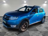 La Dacia bleue est garée dans une pièce au sol carrelé.