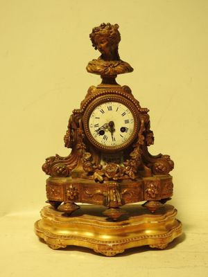 une horloge en or surmontée d'un buste