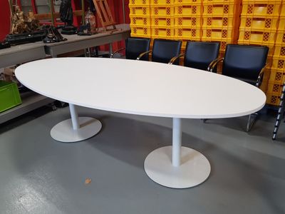 a white oval table in a room with chairs