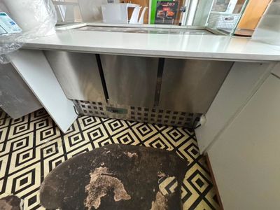 un sol sale dans une cuisine équipée d'un évier et d'un réfrigérateur