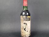 an old bottle of red wine sitting on top of a table