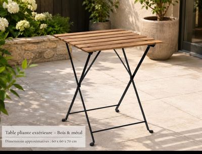 une petite table en bois posée sur une terrasse, à côté d'une plante en pot
