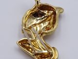 a close up of a gold plated bird brooch on a white surface