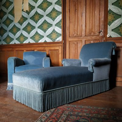 un canapé bleu et un fauteuil bleu dans une pièce aux murs lambrissés