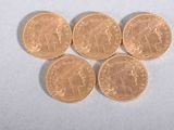 six gold sovereigns sitting on top of each other on a white surface