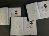 four books with drawings of people on them sitting on a table
