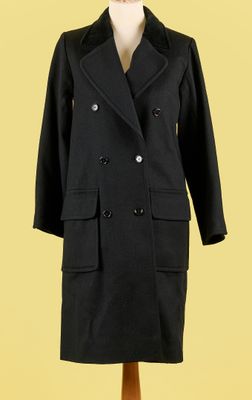 un manteau noir posé sur un mannequin, devant un fond jaune