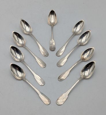 six cuillères en argent disposées en cercle sur une surface grise