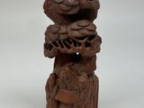 une vieille statue en bois représentant un oiseau avec un panier sur la tête