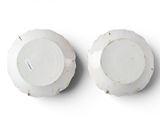 two white plates on a white surface with a white background