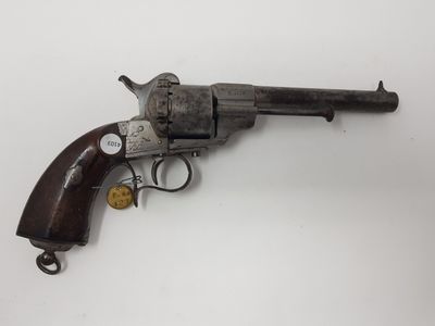 un vieux revolver avec une poignée en bois sur une surface blanche