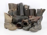 many pairs of old boots sitting on a white surface