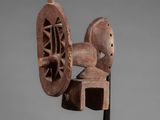 a wooden sculpture of a spinning wheel on a stand