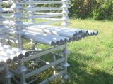 un banc blanc fait de tuyaux, posé dans l'herbe