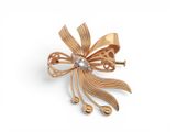 an image of a gold bow brooch with a diamond in the center