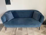 the couch is blue and has two pillows on top of it