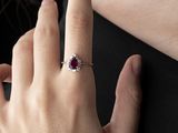 someone is wearing a ring with a red stone on it