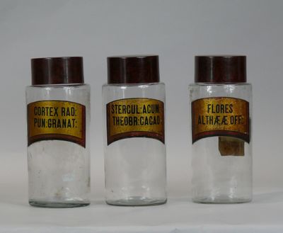 three glass jars with labels on them sitting on a table