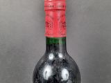 bottle of red wine with a red cap on a grey background