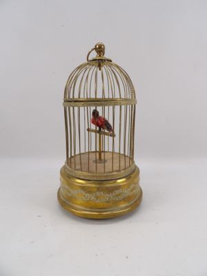 un oiseau doré dans une cage posée sur une table blanche