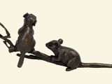 two small metal mice sitting on a tree branch