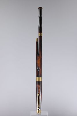 un stylo au corps en bois et aux finitions dorées, posé sur un socle